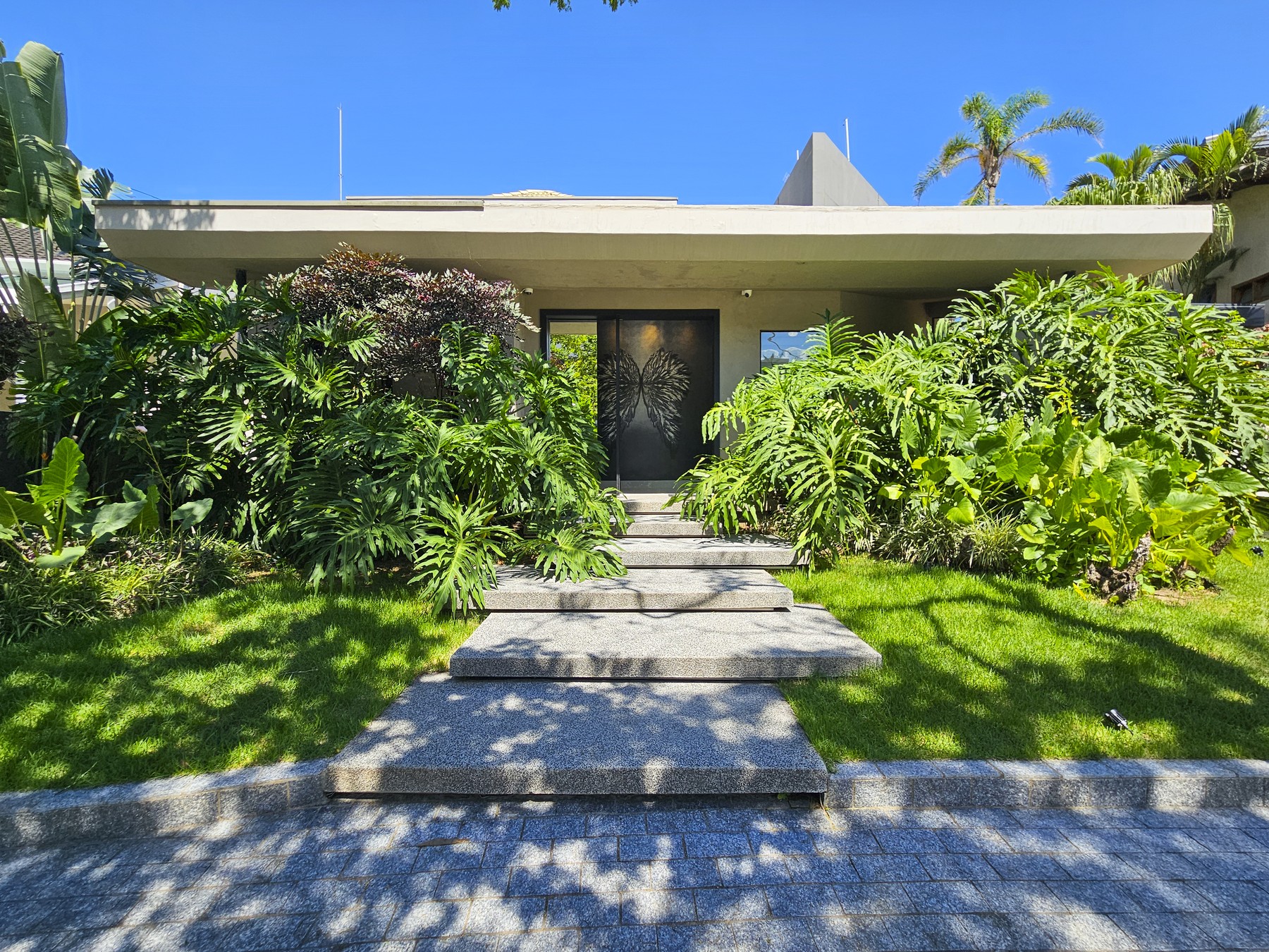 Entrada de uma residência cercada por paisagismo tropical