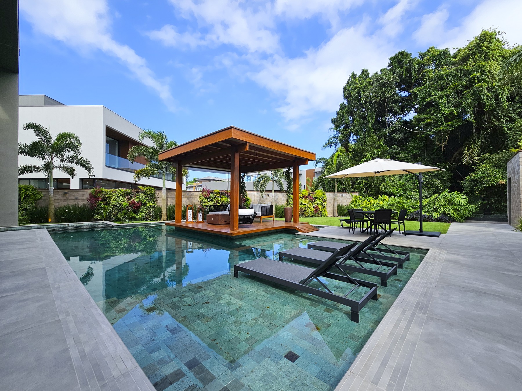 Área de lazer com piscina, espreguiçadeiras e gazebo